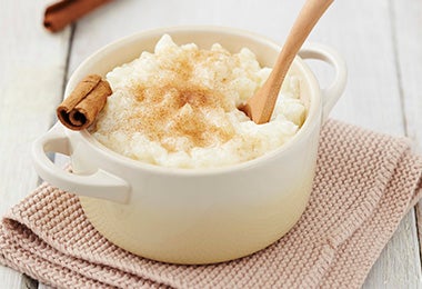 Una porción de arroz con leche, lychees y canela con una cuchara de madera