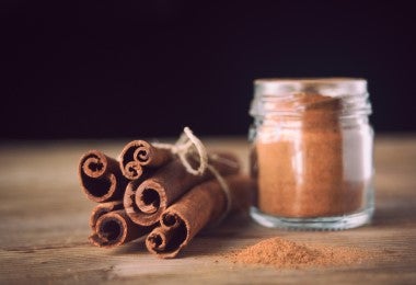 Racimo de clavos de canela junto a una piza y un recipiente de canela en polvo para mazamorra morada.