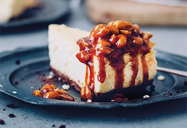Porción de cheesecake en salsa de chocolate y maní para celebrar su Día Internacional