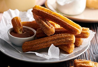 Churros recién hechos junto con un dip de crema de pudín de chocolate