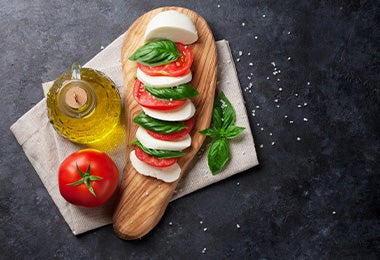 Ensalada caprese con aceite de oliva y un par de hojas de albahaca en toma cenital.