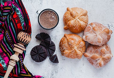 Cuatro panes de rellenos junto con una taza de chocolate, todos cocinados con cardamomo