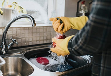 Persona lavando exprimidor de cítricos con agua y con jabón en un lavaplatos