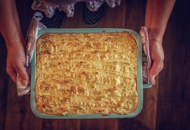 Torta de ñame en bandeja hirviendo sostenida por una persona.