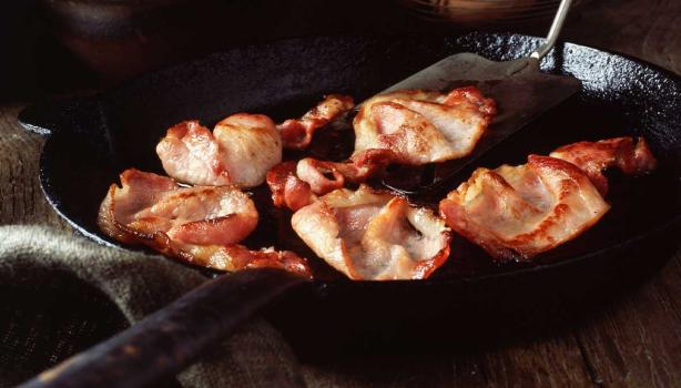 Deliciosa panceta cortada siendo fritada en un sartén