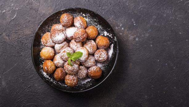 Plato de buñuelos de yuca espolvoreados vistos desde un ángulo cenital.